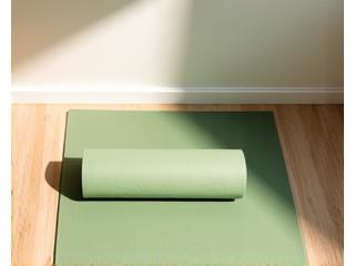Eine aufgerollte, hellblaue Yogamatte auf einem Holzfußboden, bereit für eine Session.